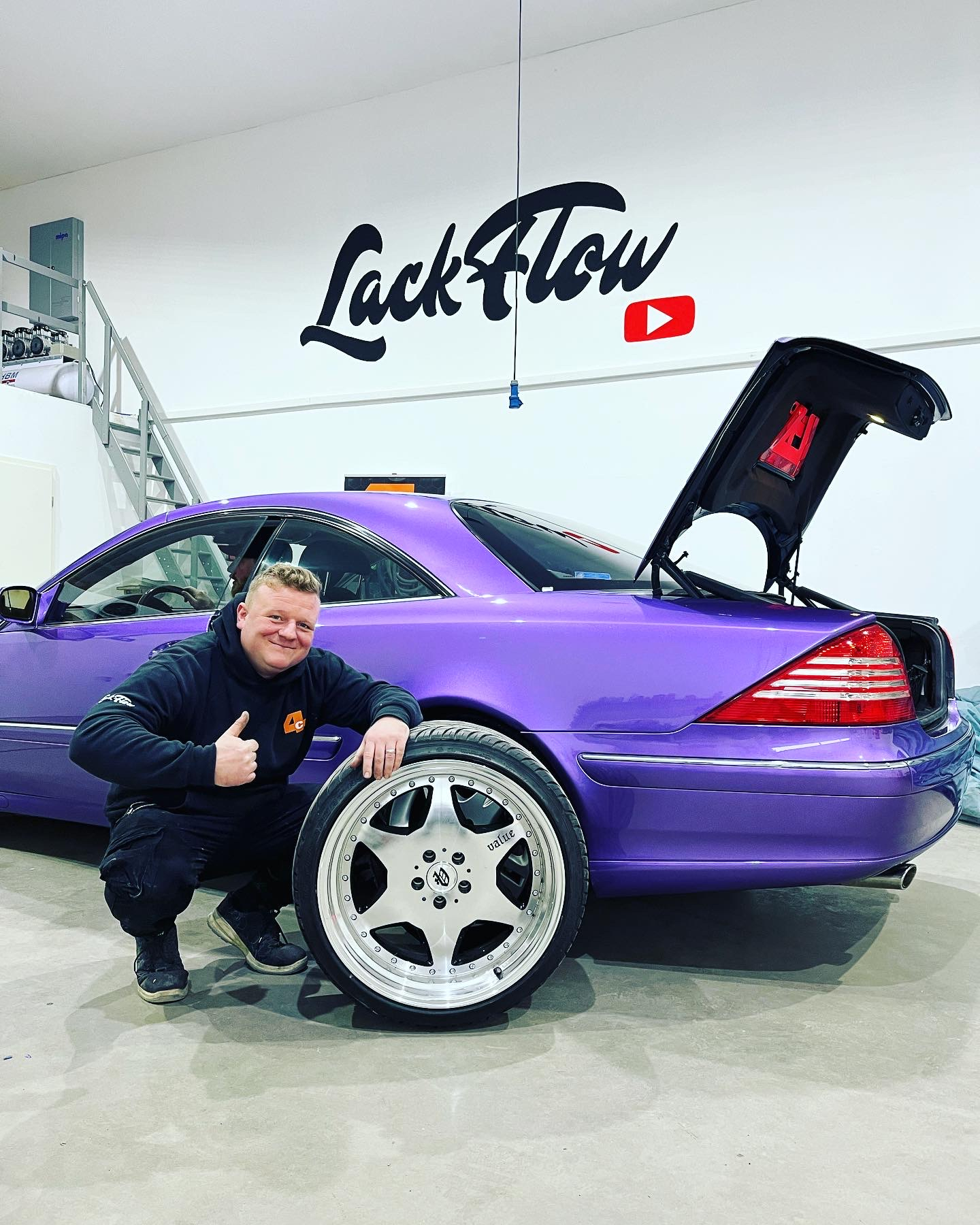 Mann mit Reifen vor lila Auto